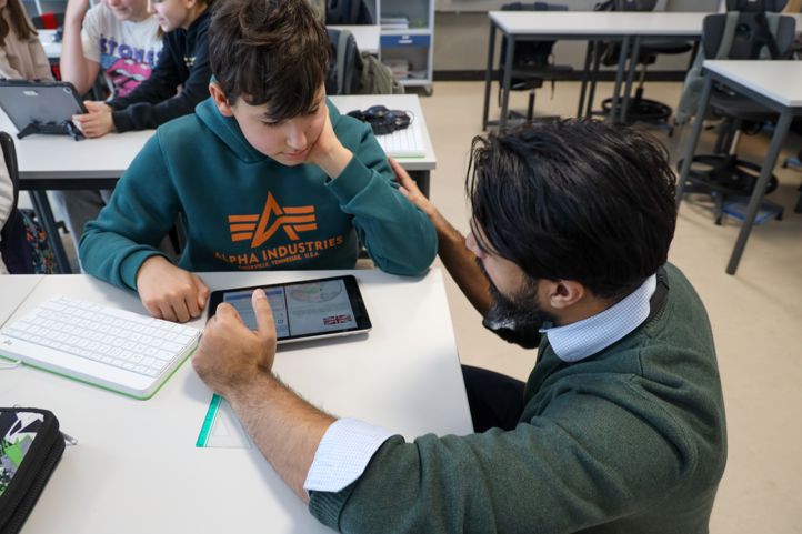 En lærer veileder en elev som arbeider på læringsbrettet.