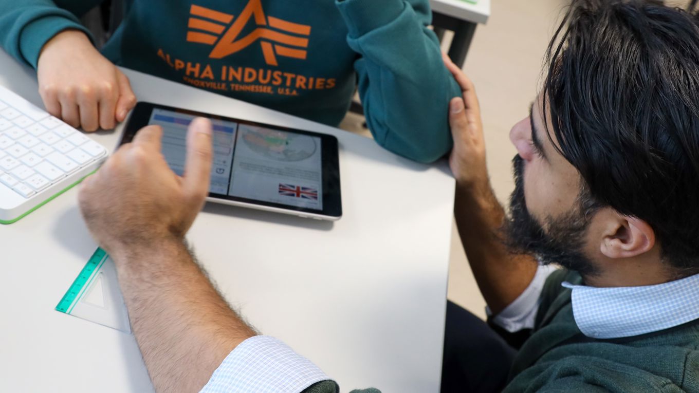 En lærer veileder en elev som jobber på læringsbrettet