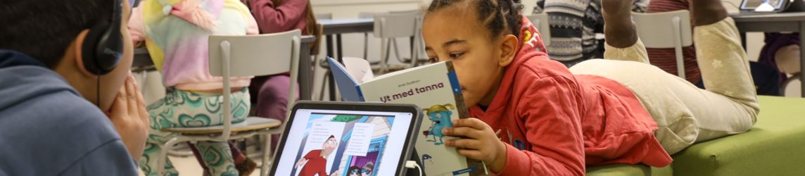 Elever som leser i et klasserom. Noen leser i bok og noen på læringsbrett. 