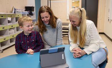 En elev, en mor og en lærer på en utviklingssamtale med et læringsbrett foran seg