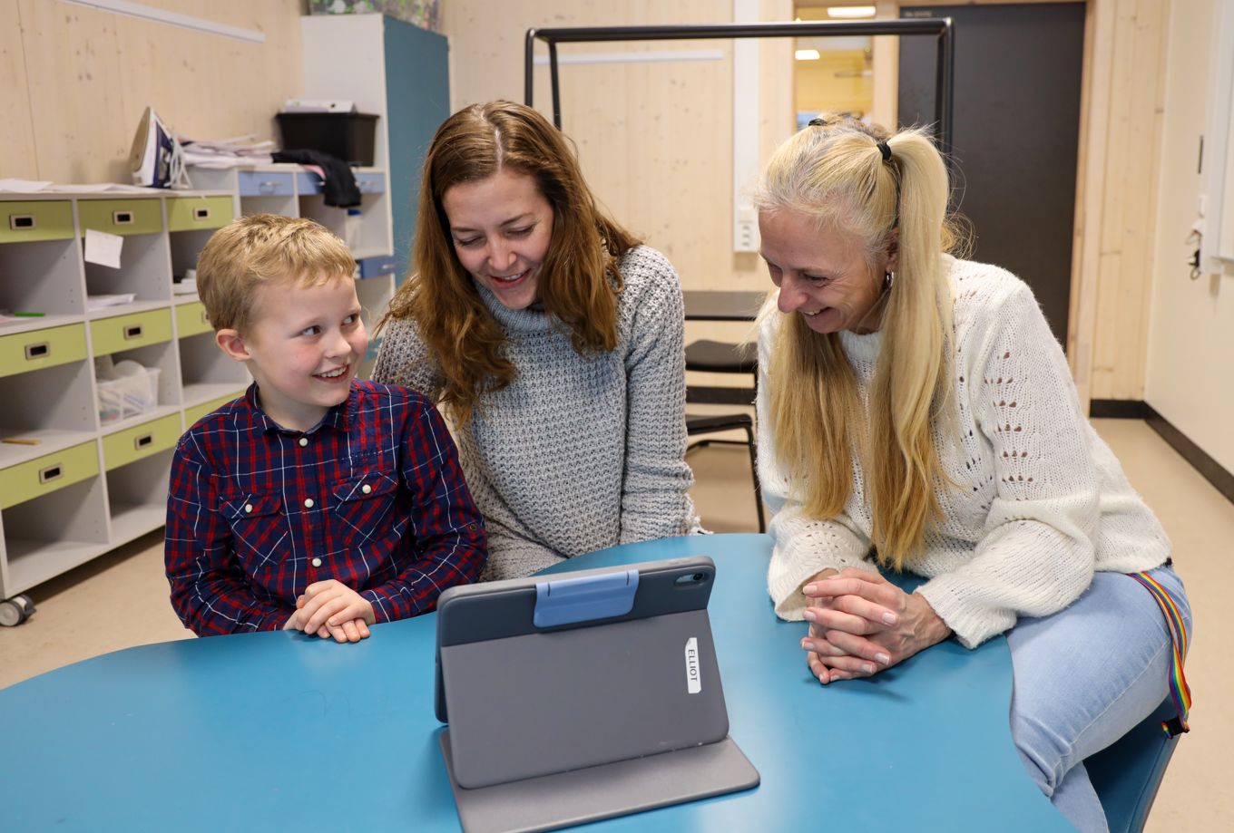 En elev, en mor og en lærer på en utviklingssamtale med et læringsbrett foran seg