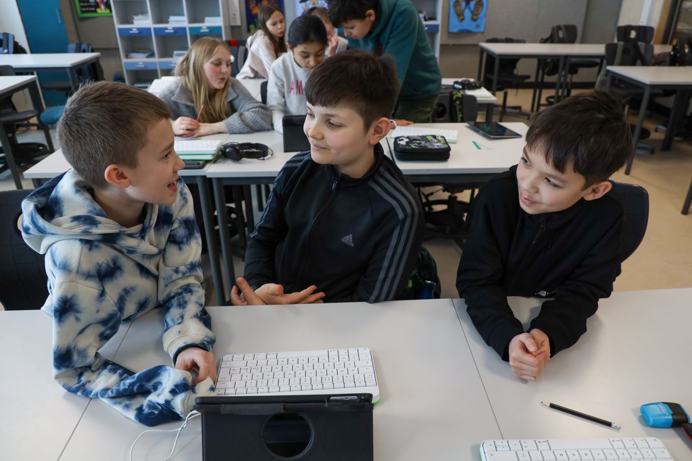 Elever i et klasserom som diskuterer innhold på et læringsbrett