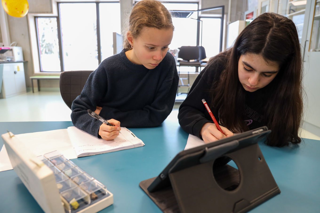 To elever som jobber med lekser, på læringsbrett og i bok